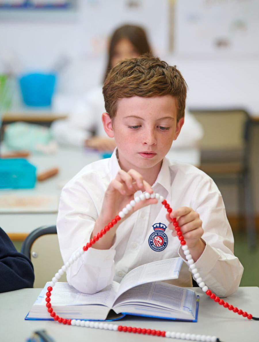 Primary School pupil using counting beads during a maths lesson at King's College, Alicante