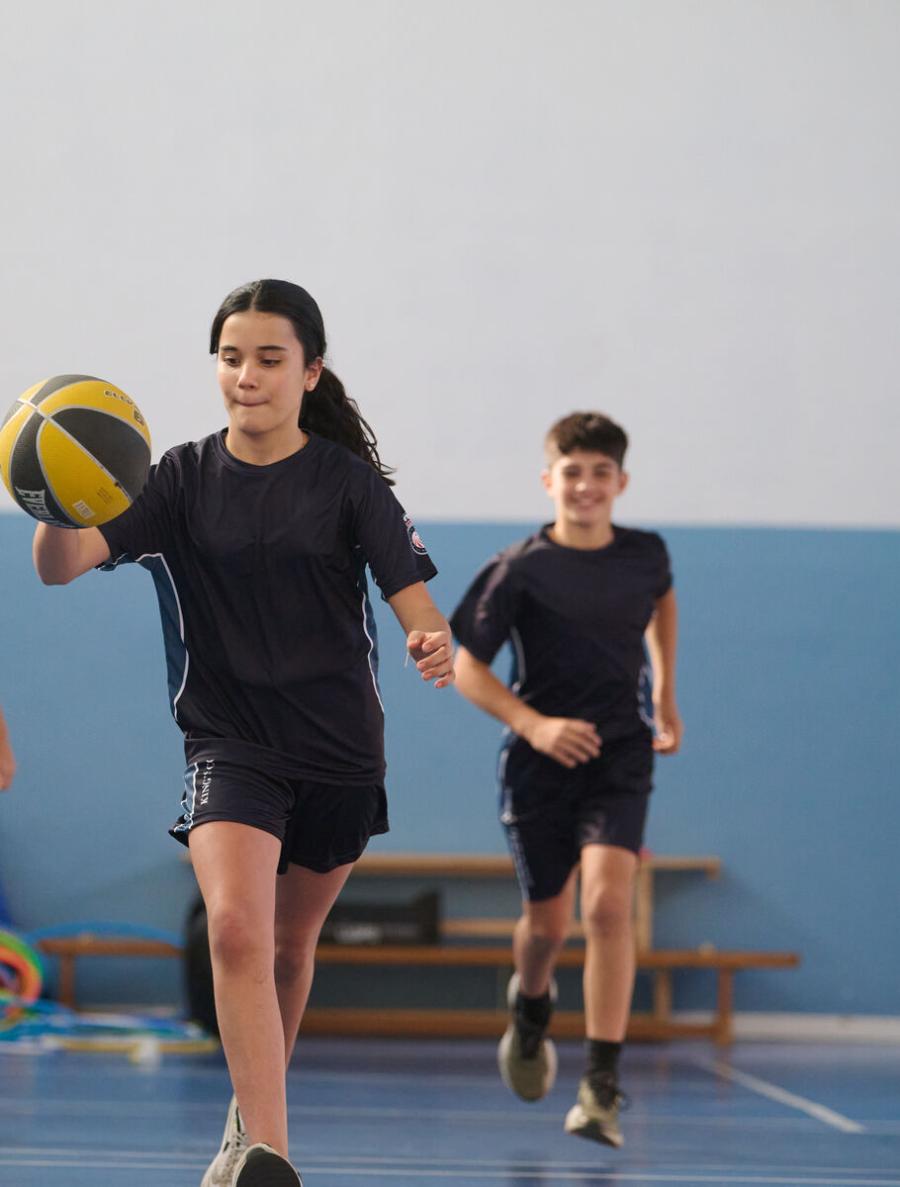 Estudiantes de Secundaria jugando al baloncesto en el pabellón deportivo en King's College, Alicante