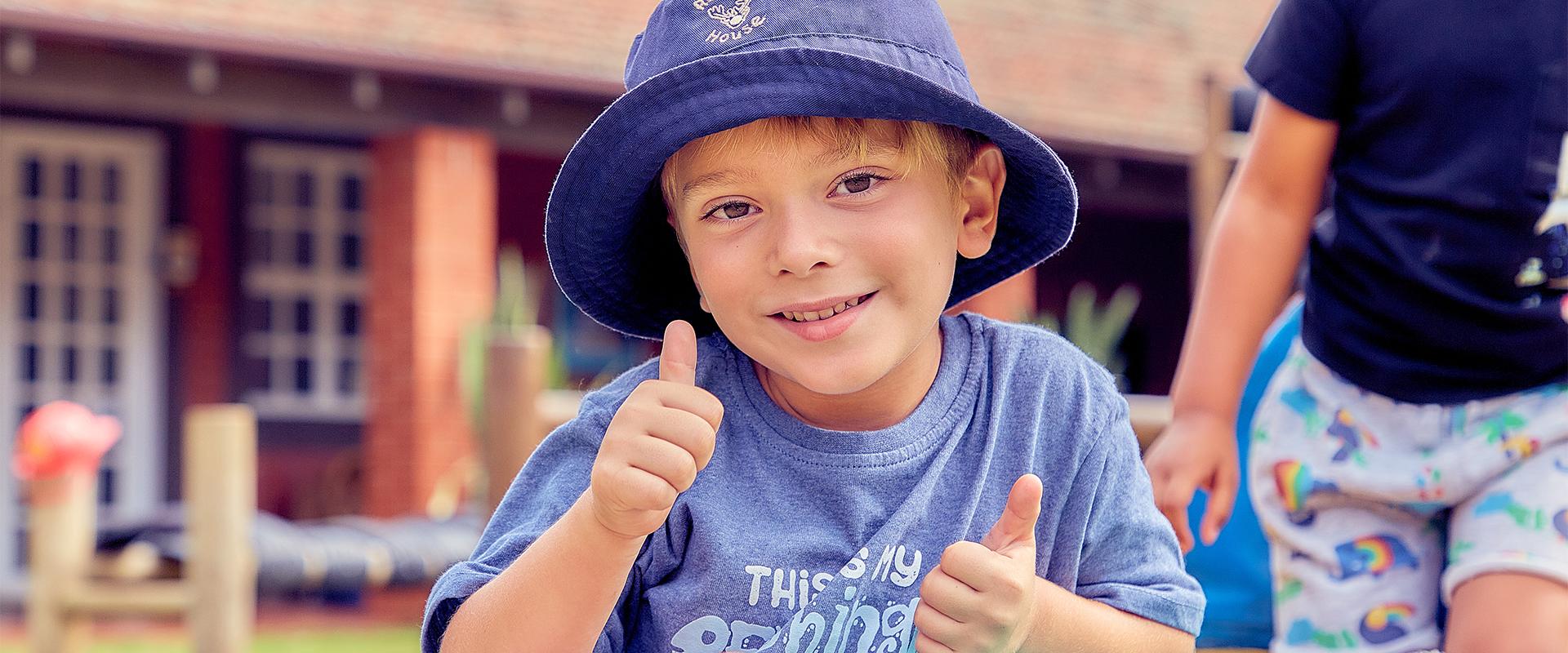Boy wearing a hat with a thumbs up gesture