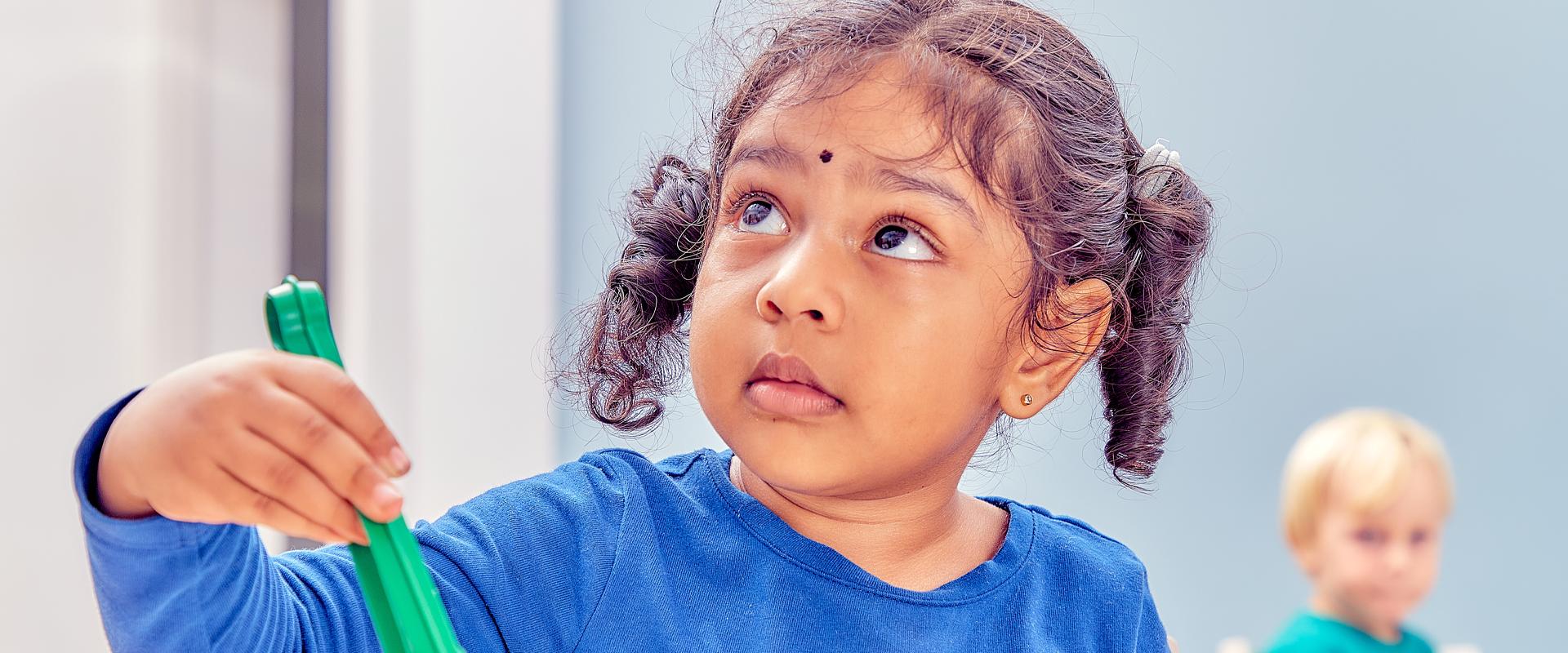 girl holding a utensil looking up towards the left