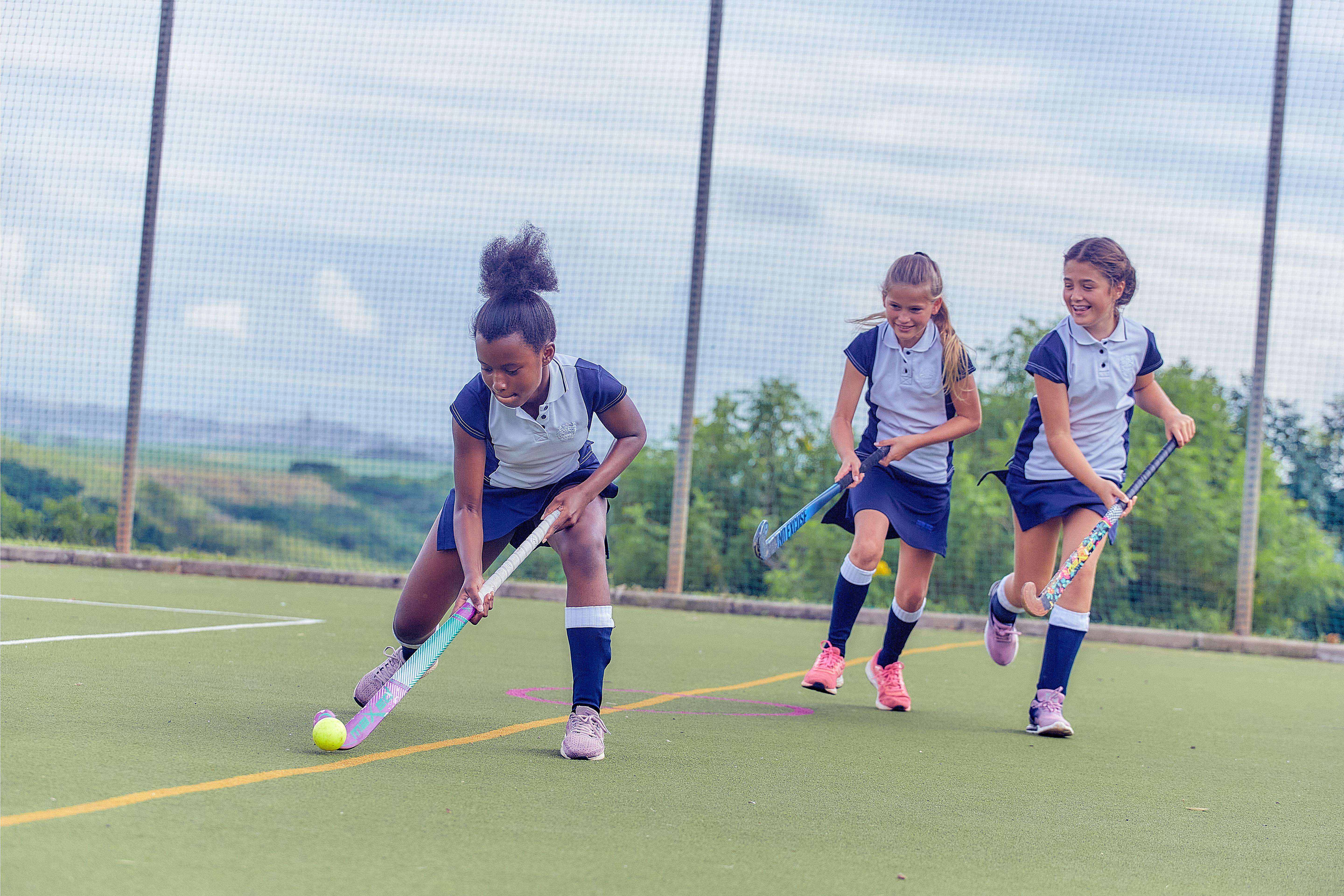 Girls playing hockey on Astro turf