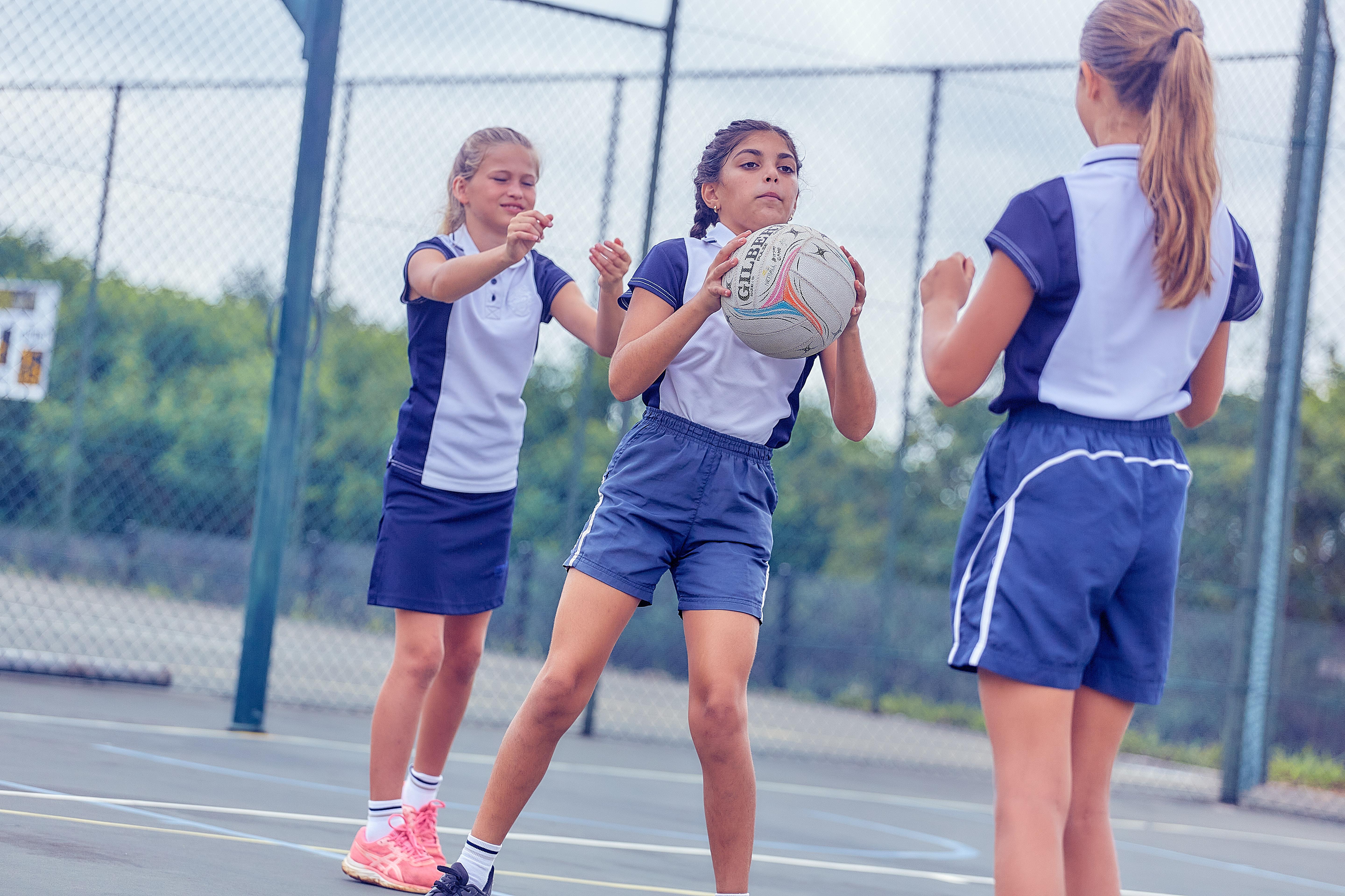 Three girls playing netball