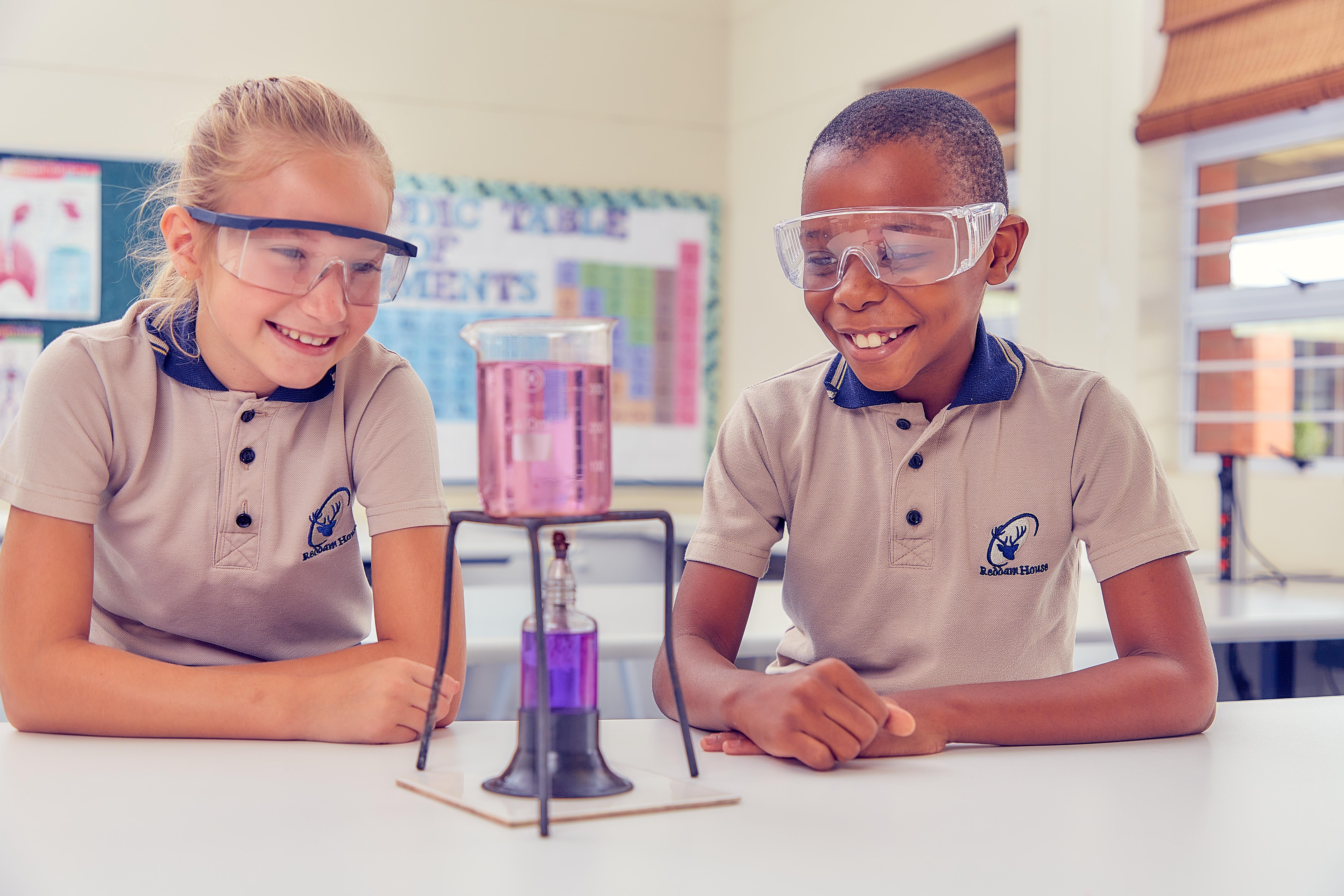 Two girls sitting together carrying out a science experiment