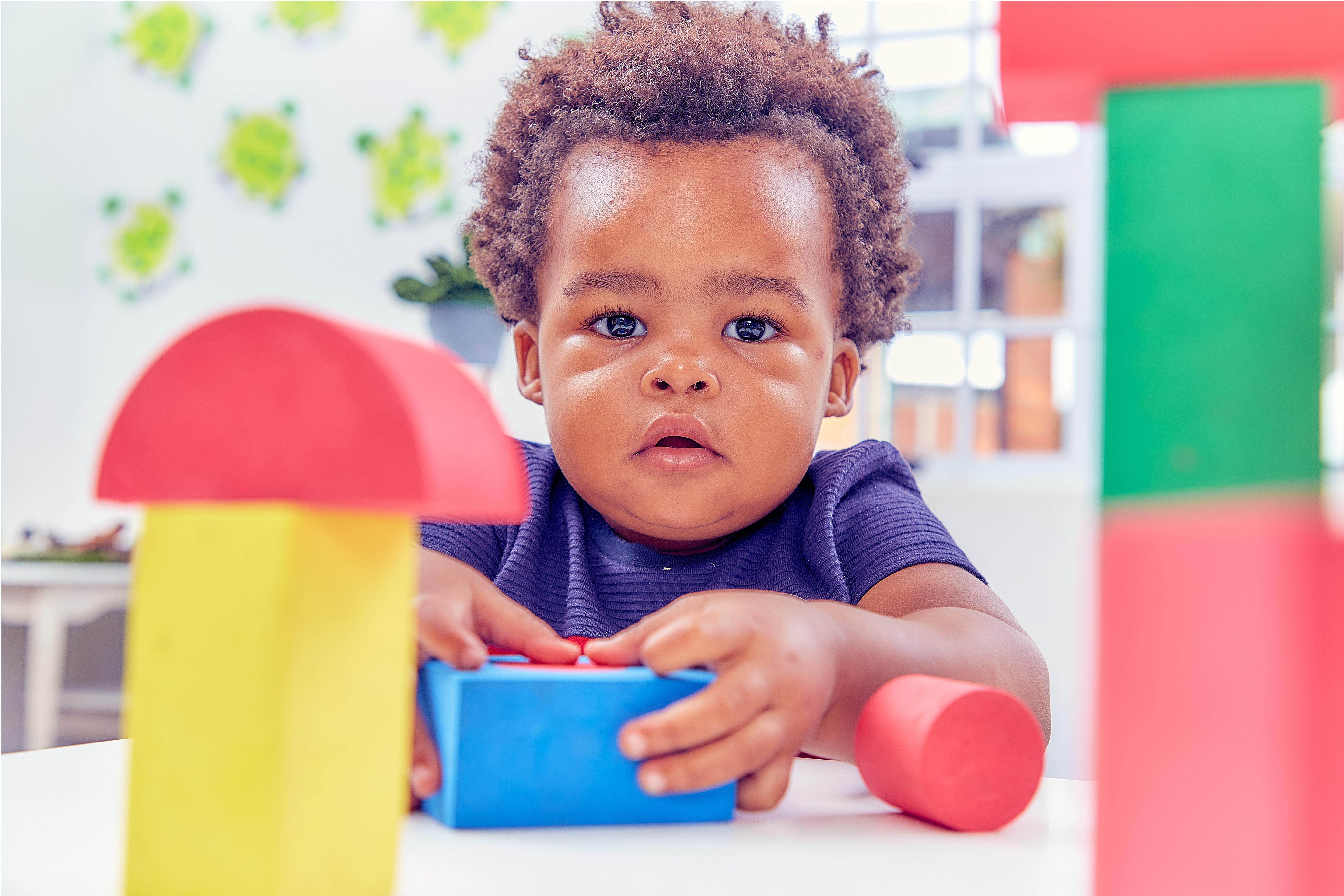 Small child looking at the camera holding building blocks