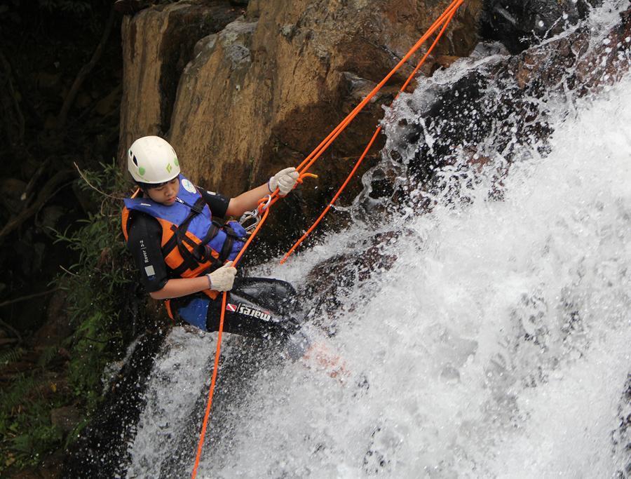 Aluno praticando canyoning em uma cachoeira durante um camp de férias internacional do Inspired Education Group