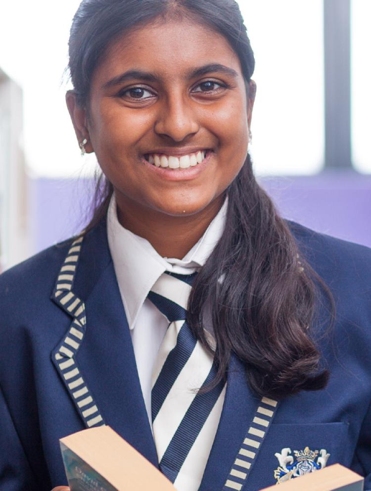 Girl holding a book and smiling at the camera