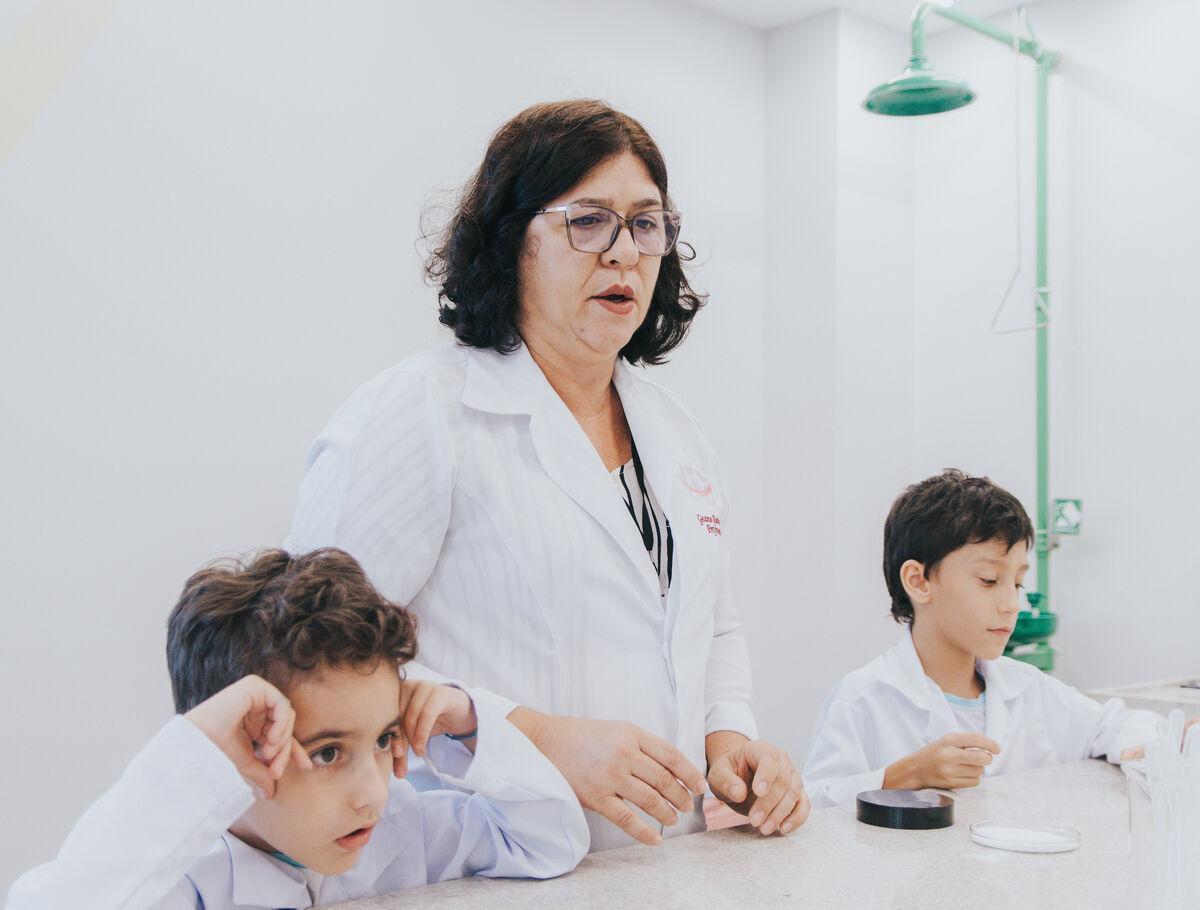 Professora orientando alunos do Ensino Fundamental I em experimento no laboratório de ciências da Escola Eleva Recife