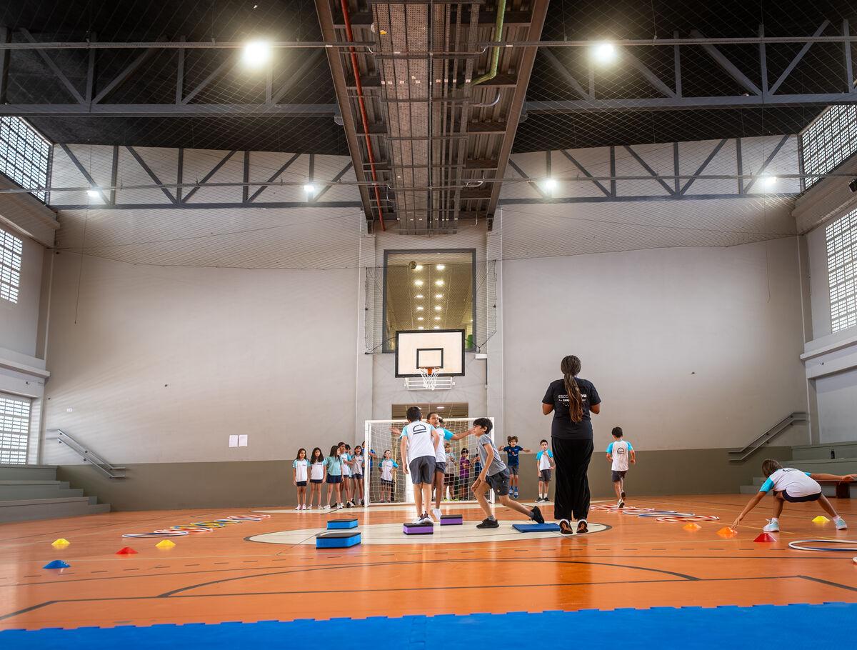 Alunos em aula de Educação Física na quadra poliesportiva coberta da Escola Eleva Recife