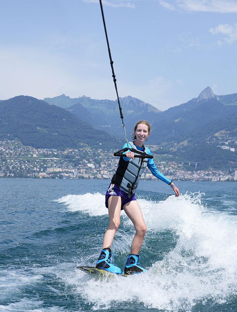 Aluno praticando wakeboard em um lago nos Alpes Suíços, representando os acampamentos de férias e de enriquecimento premium da Eleva