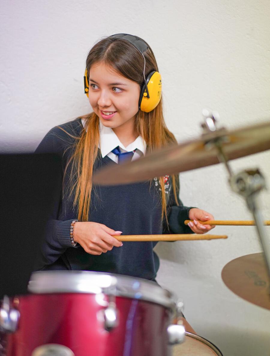 secondary school student playing drums in music lesson