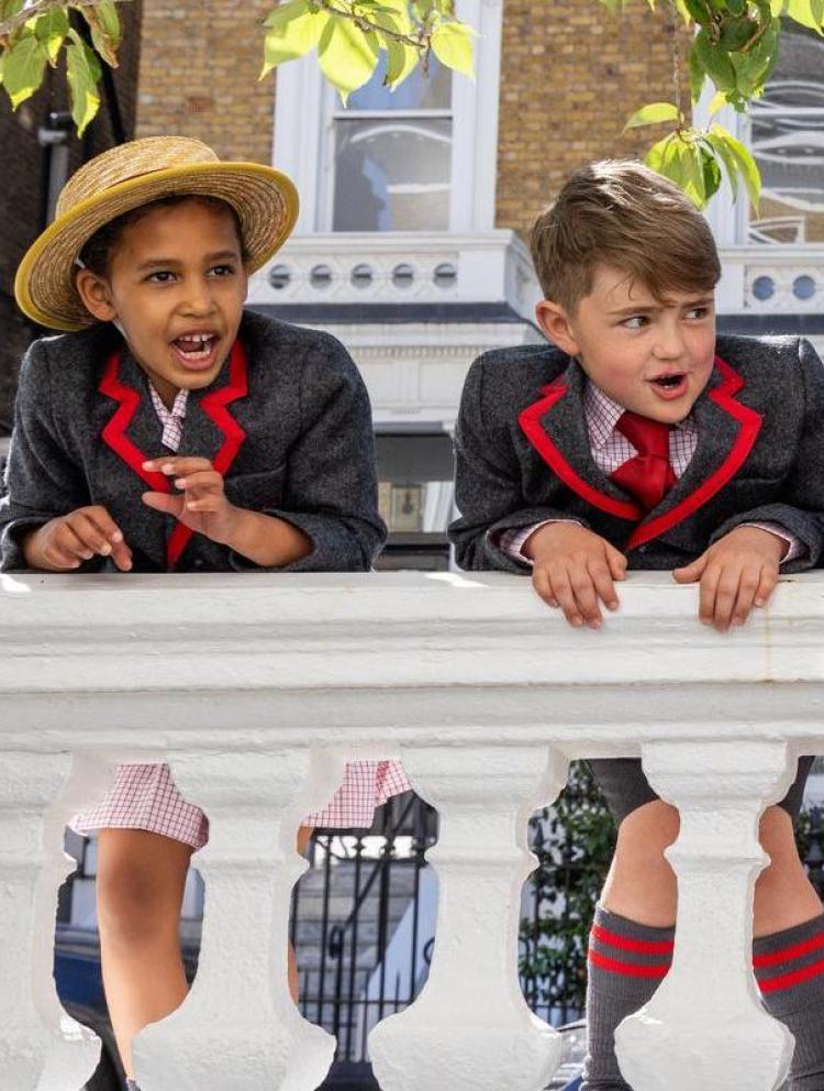 Five Wetherby Pembridge Pre-Prep pupils in blazers and straw hats leaning over a white balustrade