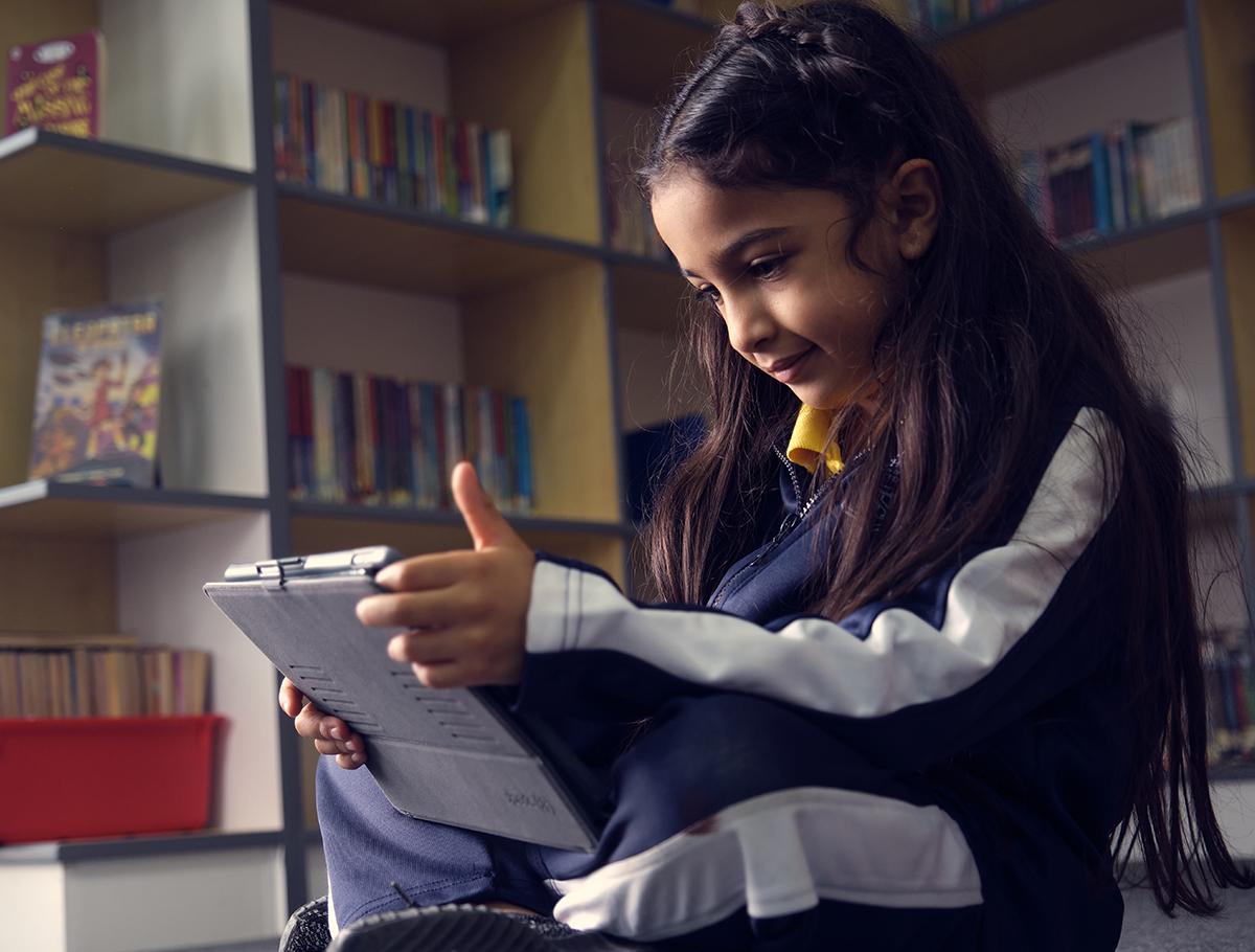 Girl-sitting-cross-legged-looking-at-ipad-in-library